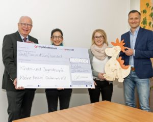 Der geschäftsführende JUMO-Gesellschafter Bernhard Juchheim übergibt den symbolischen Scheck an Carina Hillenbrand, Fundraiserin der „Kleinen Helden“. Theresa Kümmel, Mitarbeiterin der JUMO-Marketingabteilung und Marketingleiter Michael Diegelmann halten das Maskottchen des gemeinnützigen Vereins in den Händen (v.l.n.r.).